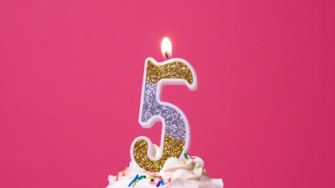 粉色背景上燃烧五颜六色蜡烛的生日蛋糕。慢动作周年视频横幅。