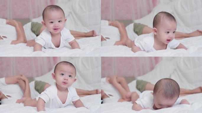 可爱的亚洲新生男婴躺在白色床上玩耍，笑容满面。而你妈妈在附近照顾。小天真的新生婴儿可爱的孩子在生命的