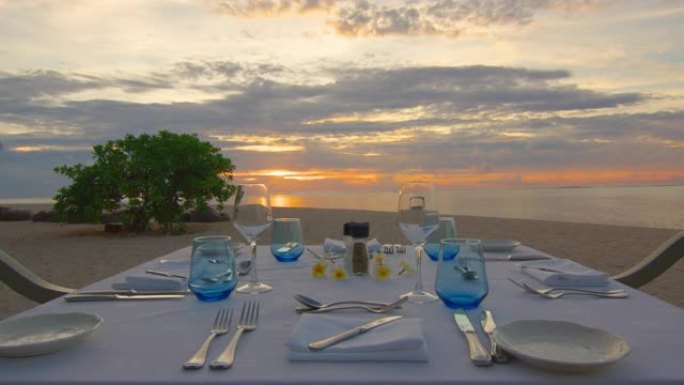 POV来自海滩上摆放的桌子和椅子，在毛里求斯受欢迎的旅游目的地观看日落，享受浪漫的晚餐