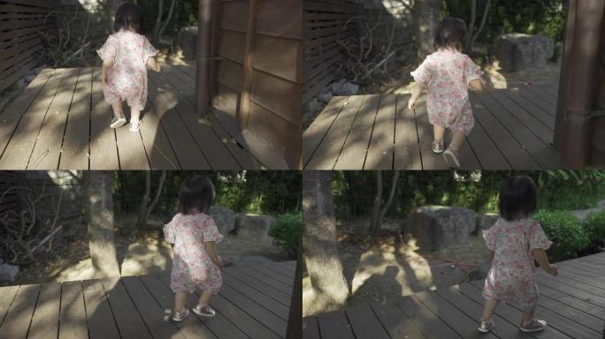在阳光明媚的日子里，一个穿着和服的日本女婴在她传统木屋的室外走廊上摇摇晃晃地拍摄了慢动作。