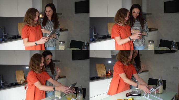 快乐的母女俩在家一起准备早餐，在互联网上阅读烹饪博客，使用数字平板电脑，母亲和青少年制作健康的水果饮