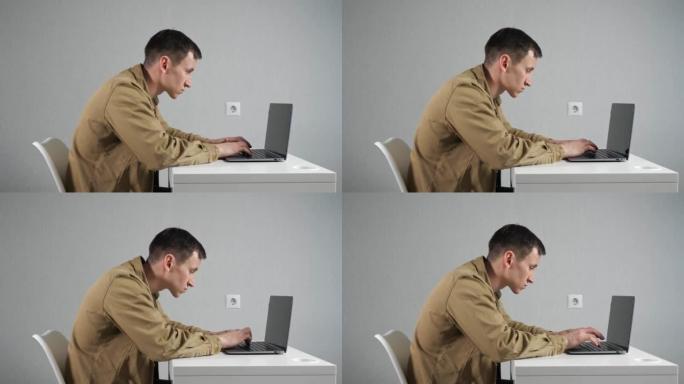 脖子弯曲的男人员工在办公室的笔记本电脑上工作