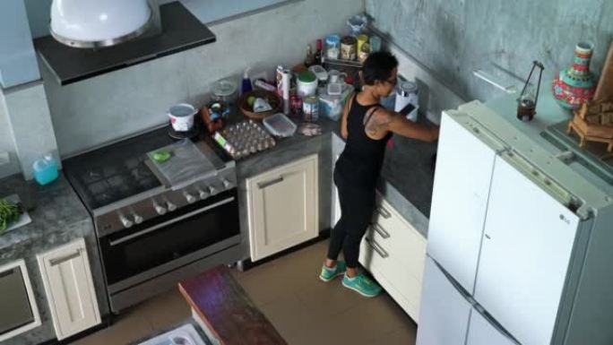 成熟的泰国女性在厨房使用智能手机