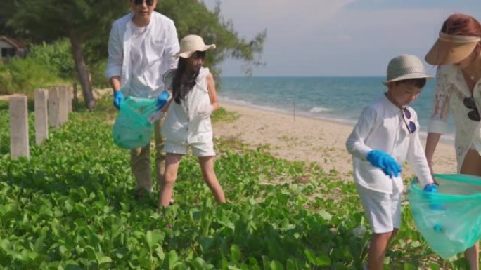 快乐的亚洲家庭与垃圾袋清洁区一起在海滩上。