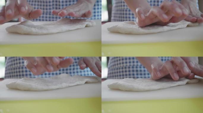 男人的手在家里用白面粉在轻木桌上揉披萨面团的特写