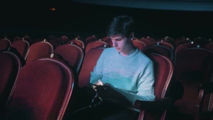 一个空荡荡的剧院里的孤独男人正在打电话，看着新闻。看电话。
中场休息