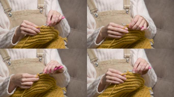 特写镜头用针编织的女人。一个妇女在房间里用针编织羊毛衣服。