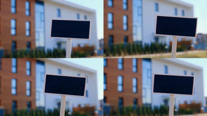 空白黑色广告牌反对新公寓楼空样机模板黑板标签房屋出租。待售公寓。在新家前签名。广告