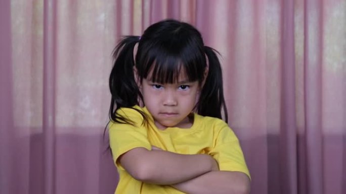 穿着黄色t恤的愤怒的亚洲小女孩在家里表现出失望和冲突。面部表情和手势的概念