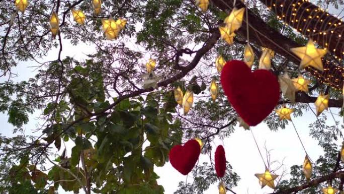 红色的心挂在树上，晚上有许多纸星星和灯光闪烁。情人节概念
