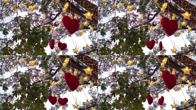 红色的心挂在树上，晚上有许多纸星星和灯光闪烁。情人节概念