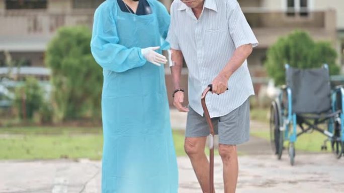亚洲华裔女性理疗师用拐杖帮助老人在公园散步