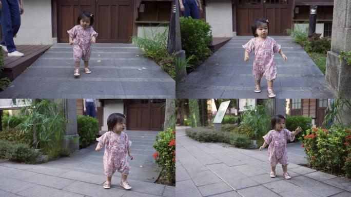 一个穿着和服的精力充沛的日本婴儿蹒跚学步的慢动作从母亲那里解脱出来，从她传统的房屋建筑中摇摇摆摆地走