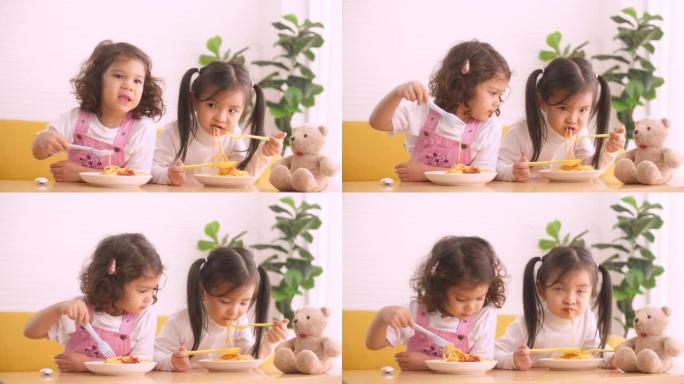 快乐可爱的小女孩一边吃意大利面一边把盘子弄得一团糟