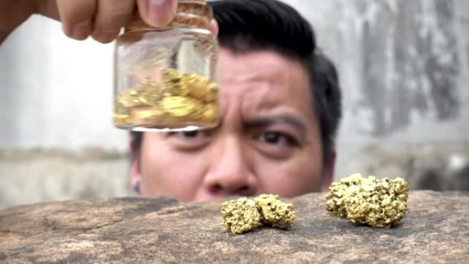亚洲人在瓶子里寻找矿山中发现的纯金矿物