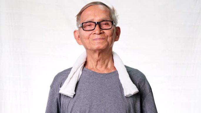 亚洲老人在家锻炼。脖子上有毛巾的成熟男人。健康的生活方式