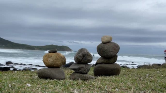 海边堆放的岩石，人们在背景上冲浪