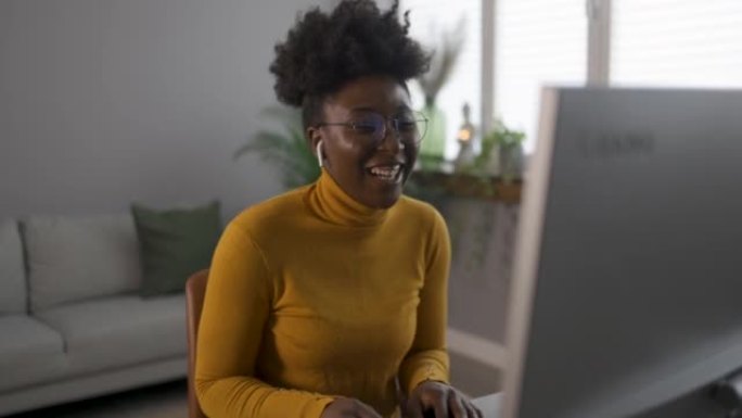 微笑的年轻非洲裔美国少女戴着耳机在笔记本电脑上通话视频。