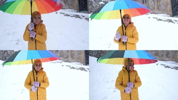 彩虹色雨伞下雪时，小女孩感到幸福