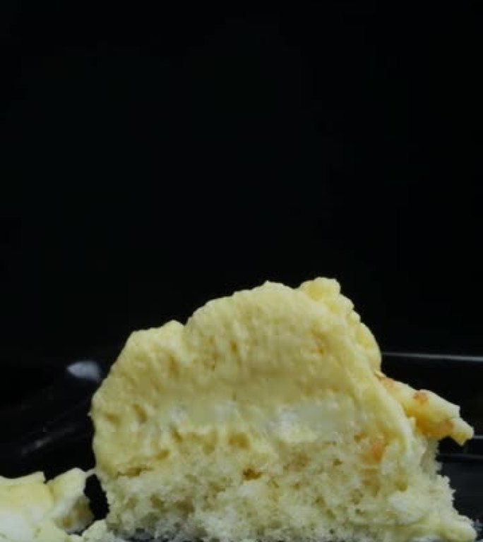 一小勺取一块香蕉味的黄色慕斯蛋糕。垂直视频，多莉拍摄。最高口味的糖果