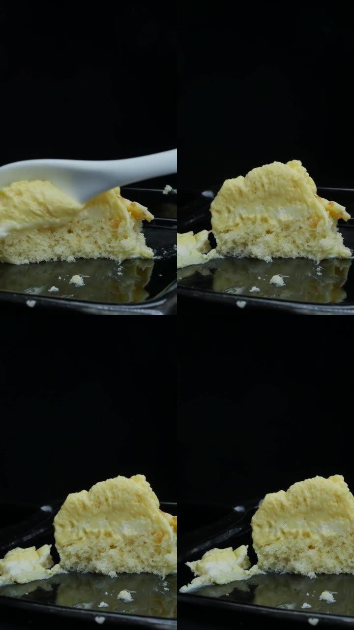 一小勺取一块香蕉味的黄色慕斯蛋糕。垂直视频，多莉拍摄。最高口味的糖果