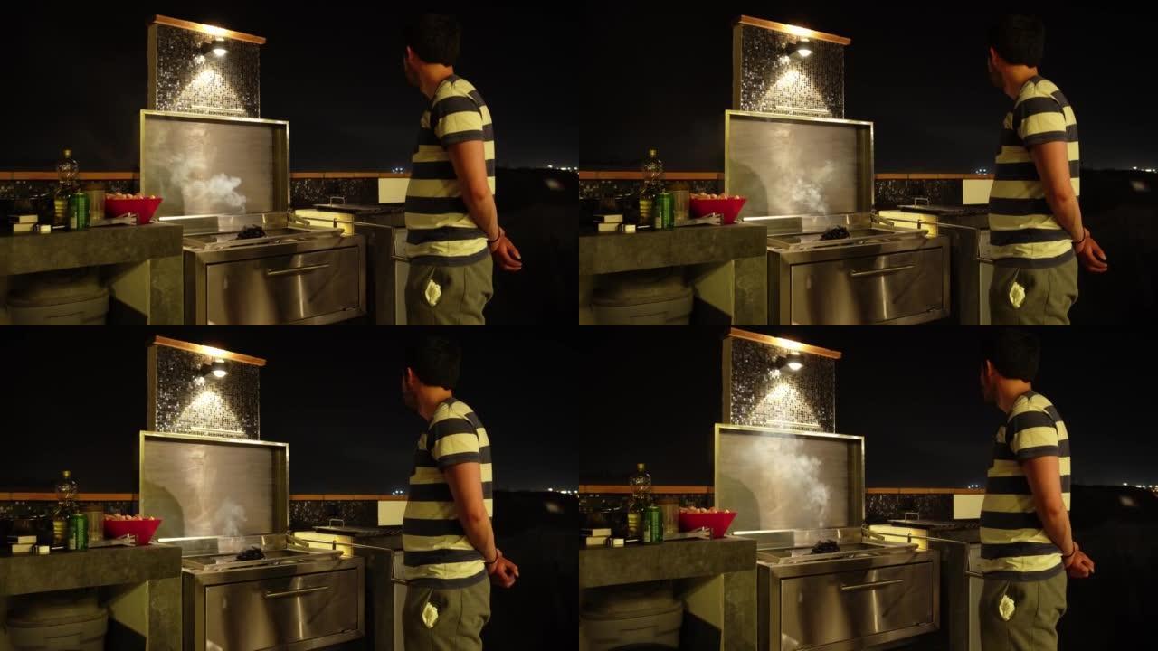 晚上，一个男人在烤架旁边，等待木炭加热，同时在4k的海滨别墅里看着天空