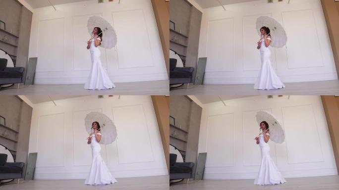 害羞的新娘穿着白色连衣裙，拿着雨伞站着摆姿势。