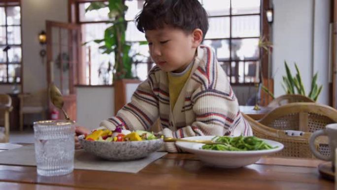饥饿的小男孩吃蔬菜沙拉