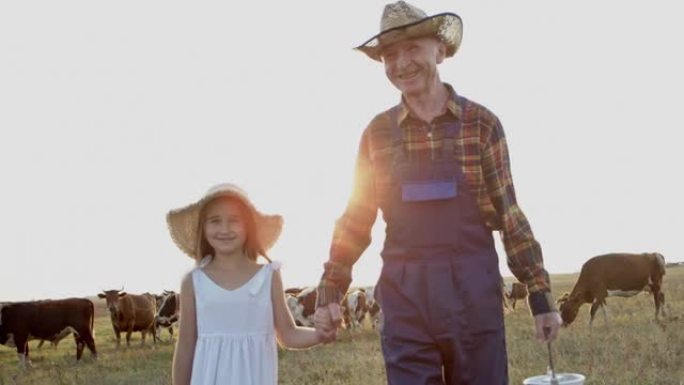 微笑的农民和小女孩在日落时分走在夏天的田野里