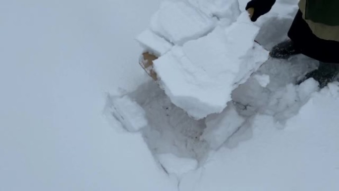 穿着长裙的女人在房子附近的院子里用铲子扫雪。铲雪，清除成堆的雪。手动除雪。暴风雪过后，冬日清洁房屋附