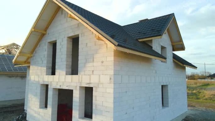 未完成房屋的鸟瞰图，加气轻质混凝土墙和正在建造的金属瓦覆盖的木制屋顶框架