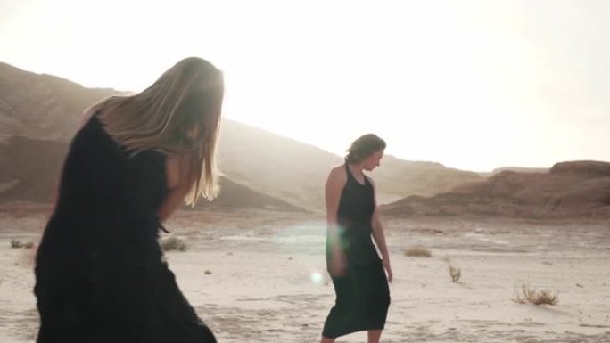 两名女子在阳光下的沙漠中疯狂地跳舞