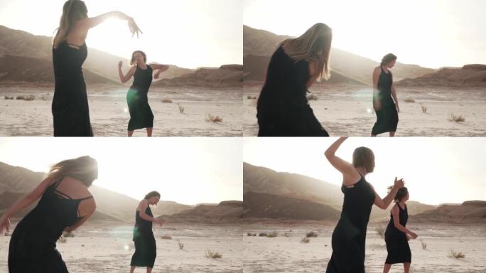 两名女子在阳光下的沙漠中疯狂地跳舞