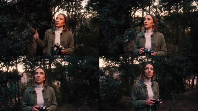 大自然中的旅行女孩，带着相机看着树木。手持