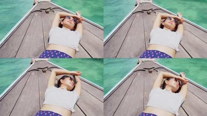 4k亚洲年轻女子在暑假过海滩泻湖的船上休息的肖像