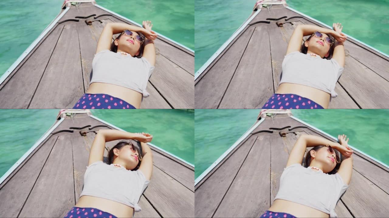 4k亚洲年轻女子在暑假过海滩泻湖的船上休息的肖像