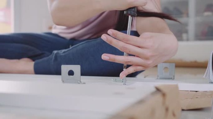 女人用螺丝刀在DIY橱柜家具上工作