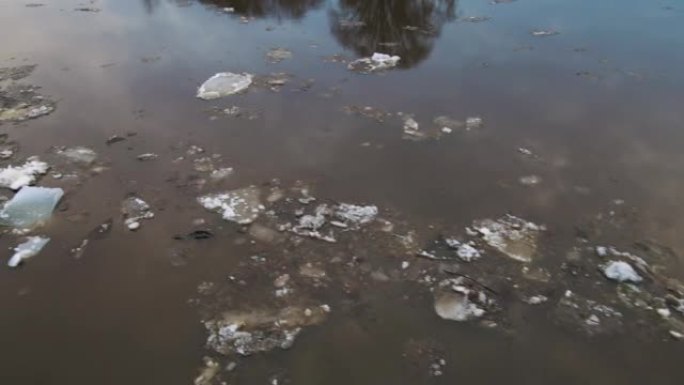 不是很脏的白色浮冰漂浮在泥泞的河上。