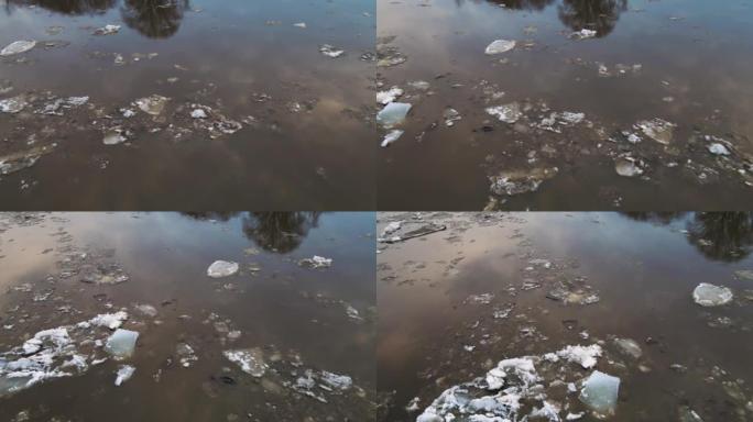 不是很脏的白色浮冰漂浮在泥泞的河上。
