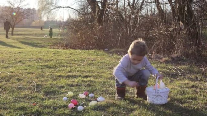 可爱的蹒跚学步的男孩，在公园的篮子里收集复活节彩蛋