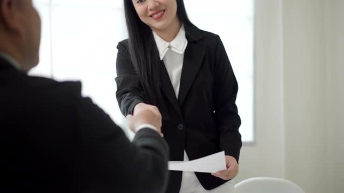 聪明的亚洲女人在求职面试前握手问候人力资源人员。快乐的女寻求者或保险经纪人提出商业交易。女商人发送简