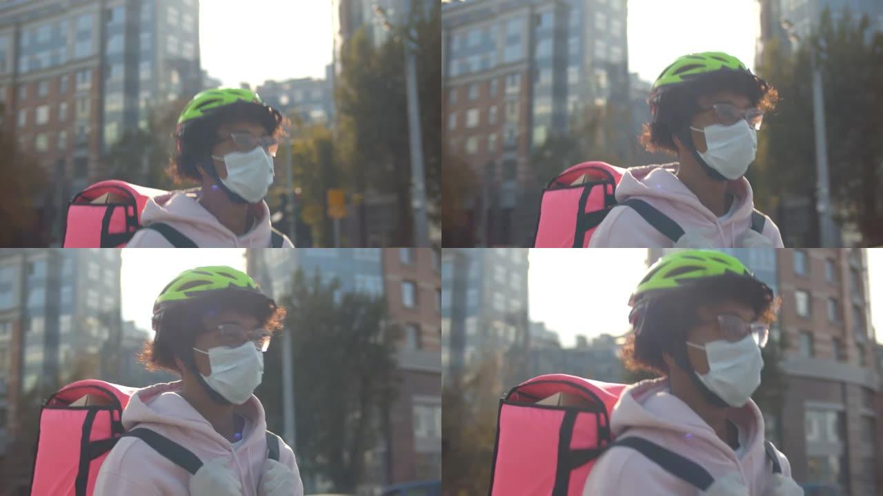 年轻的非洲裔送货员戴着防护医用口罩，提着打开的保暖袋在城市行走。