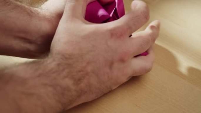 双手皱巴巴的粉色纸特写。皱巴巴的紫色床单的微距拍摄