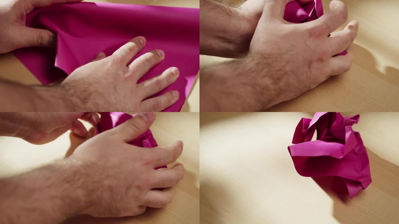 双手皱巴巴的粉色纸特写。皱巴巴的紫色床单的微距拍摄