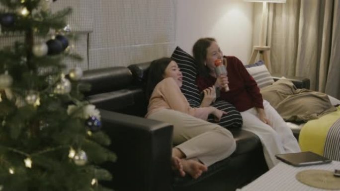 活跃的高级妈妈在家里庆祝圣诞晚会时，喜欢和女儿一起唱卡拉ok。