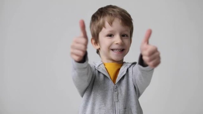 可爱的小男孩表现出竖起大拇指的手势，快乐的面部表情情感