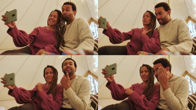 快乐、深情的情侣在野营蒙古包里用相机手机自拍