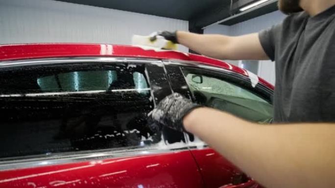 男子工人在洗车场洗红色汽车。