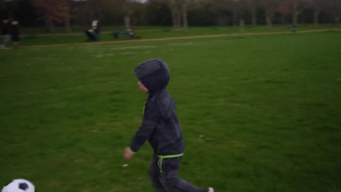 孩子们在春天公园玩得开心的幸福家庭。小孩跑。儿童男孩在绿草地上运球黑白经典足球。踢足球的人。童年，运