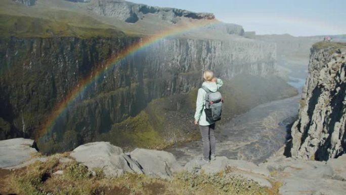 站在悬崖边缘的女人在冰岛的Detifoss瀑布附近的峡谷中往下看
